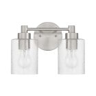 The Lyndsey - 60202 by Craftmade is a modern wall sconce with two clear glass shades and visible bulbs. It showcases a brushed metal finish and an oval mount, offering a sleek, contemporary style.