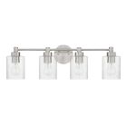 The Lyndsey - 60204 collection by Craftmade features a wall-mounted brushed nickel light fixture with four clear cylindrical glass shades. Each transparent shade displays a bulb, adding to its modern design, accented by a smooth oval base plate.